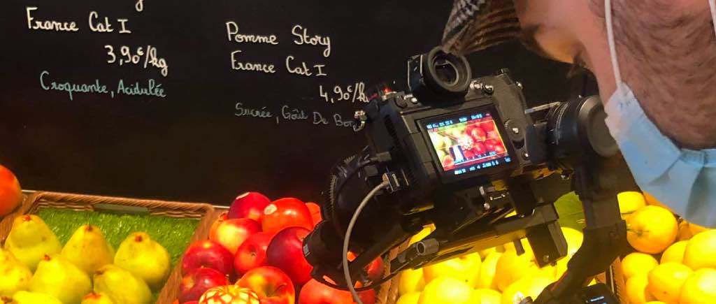 Aymeric Artus à Rungis tenant un stabilisateur Ronin S2 et un boîtier Panasonic S1H devant des légumes et fruits frais