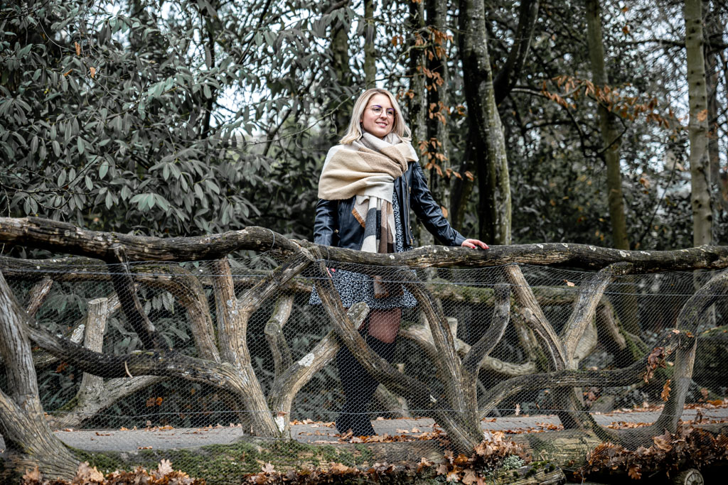 Jolie femme en robe courte et collants avec lunettes sur un pont dans un parc à Rennes