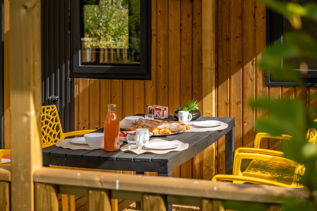 Petit déjeuner servi sur une terrasse au camping de Mesqueau avec vue extérieure