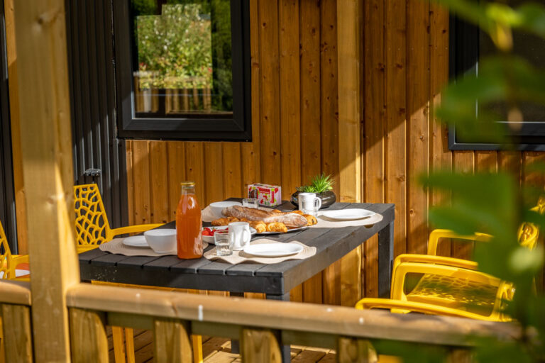 Petit déjeuner servi sur une terrasse au camping de Mesqueau avec vue extérieure