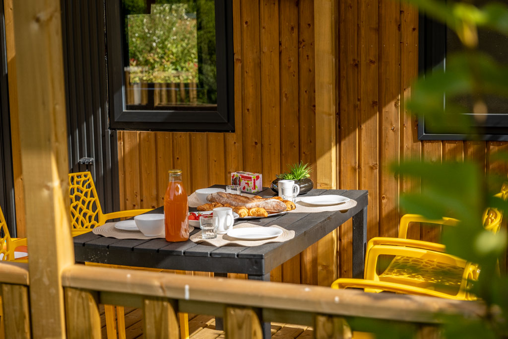 Petit déjeuner servi sur une terrasse au camping de Mesqueau avec vue extérieure