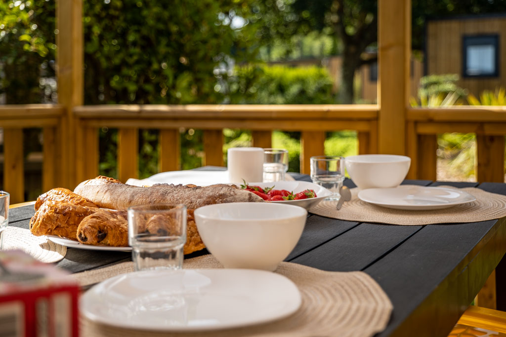Petit déjeuner servi sur une terrasse au camping de Mesqueau avec vue extérieure