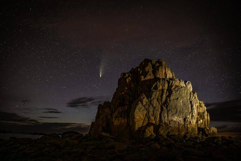 Comète NEOWISE dans le ciel étoilé au-dessus d'une aiguille rocheuse à Plougrescant, en Bretagne